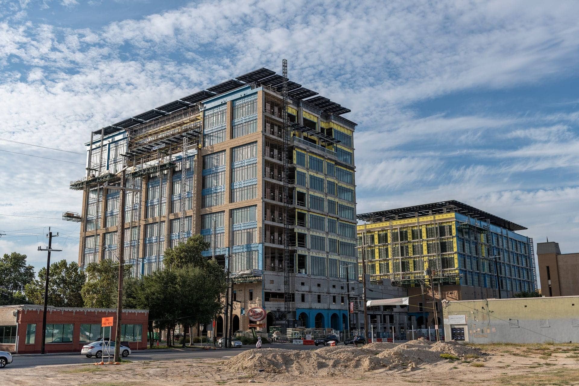 Two multi-story buildings under construction with exposed framing and scaffolding