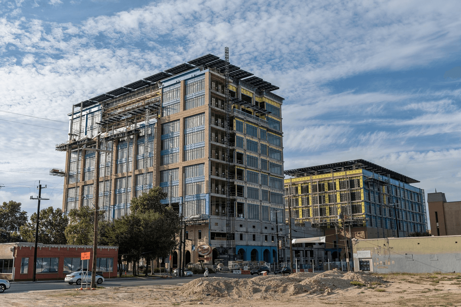 Two multi-story buildings under construction with exposed framing and scaffolding